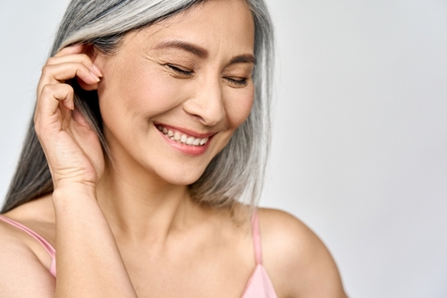 close up of a middle aged asian lady with gray hair smiling contently