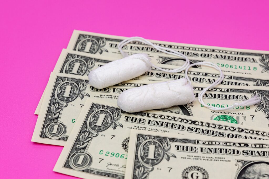 cotton tampons on top of dollar bills against a bright pink background