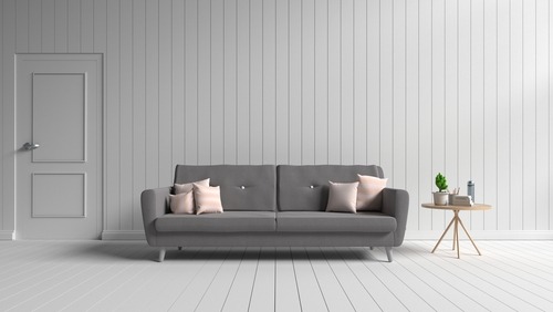 a grey square style couch with pink throw pillows against a minimalist light gray background