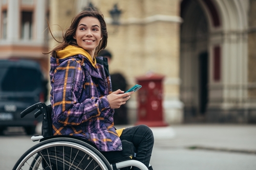 young woman in a coat and wheelchair outside on a street