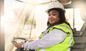 close up of black woman driving truck wearing construction vest and hat